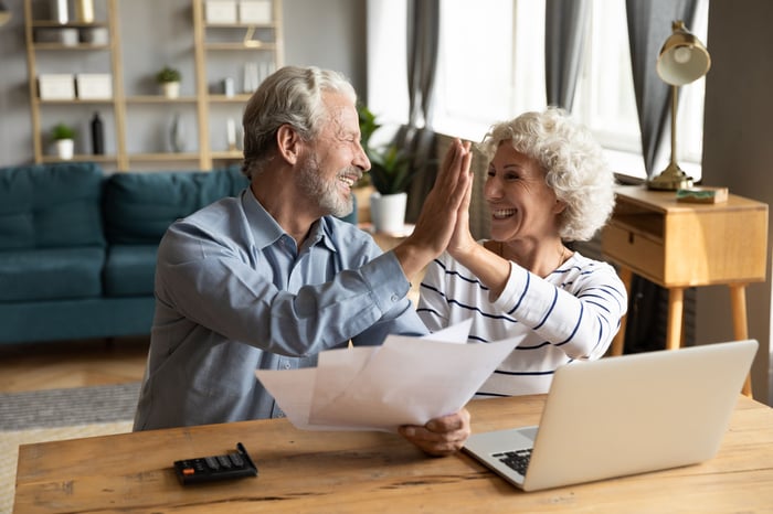 Two people holding documents and high-fiving.